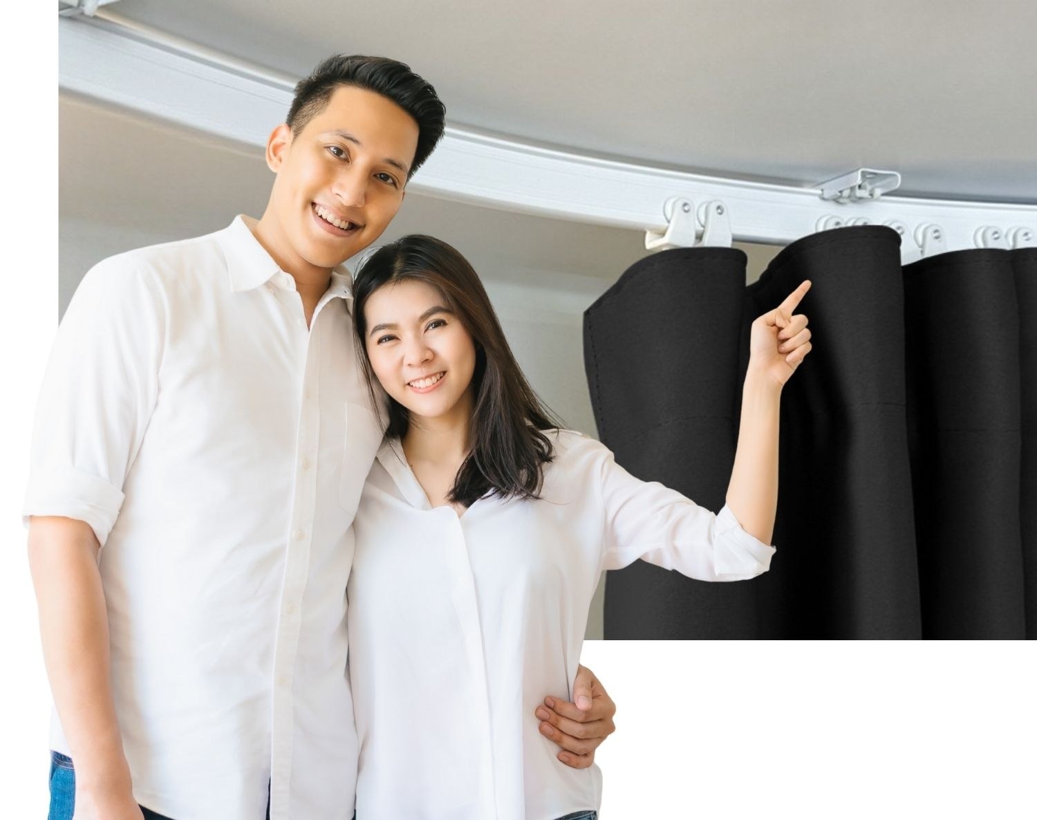 A smiling couple standing beside a curved ceiling curtain track and black curtain.
